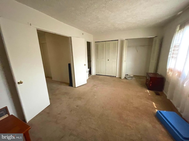 unfurnished bedroom featuring multiple closets and a textured ceiling