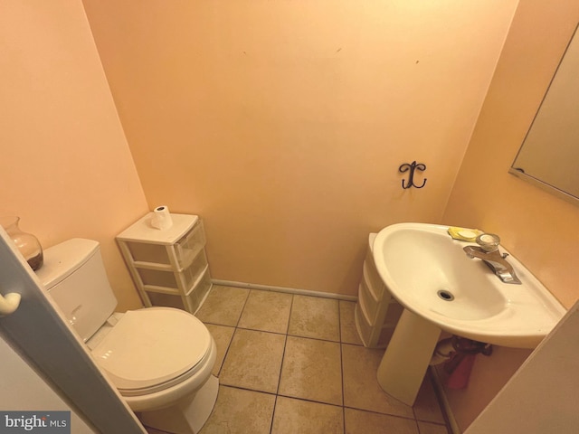 bathroom featuring baseboards, a sink, toilet, and tile patterned floors