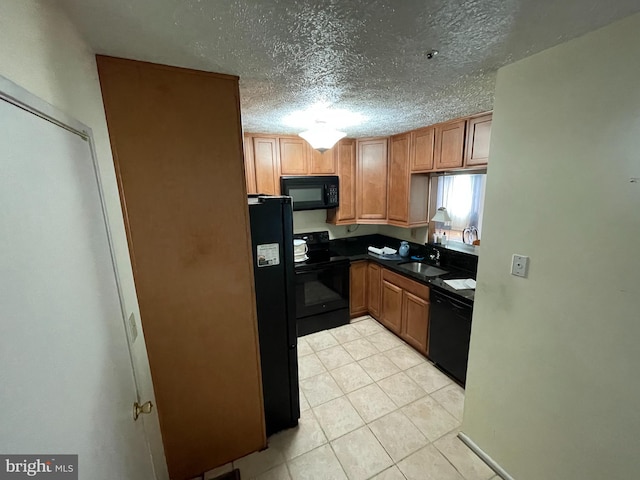 kitchen featuring light tile patterned floors, dark countertops, a sink, a textured ceiling, and black appliances