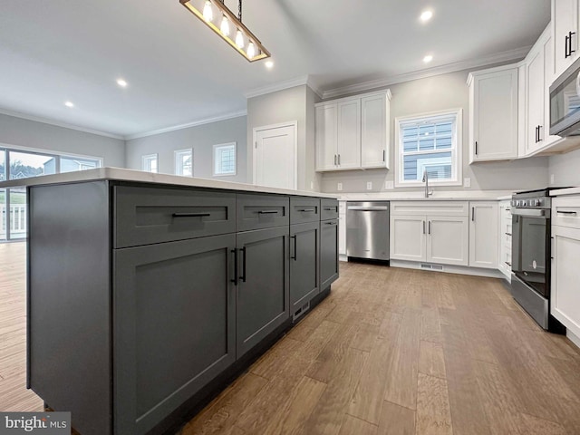 kitchen featuring light wood-type flooring, plenty of natural light, appliances with stainless steel finishes, and white cabinetry