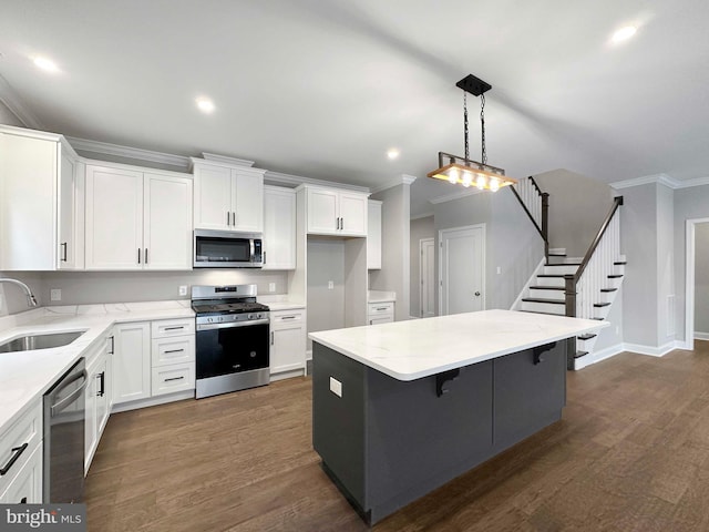 kitchen featuring dark wood-type flooring, appliances with stainless steel finishes, crown molding, sink, and light stone counters