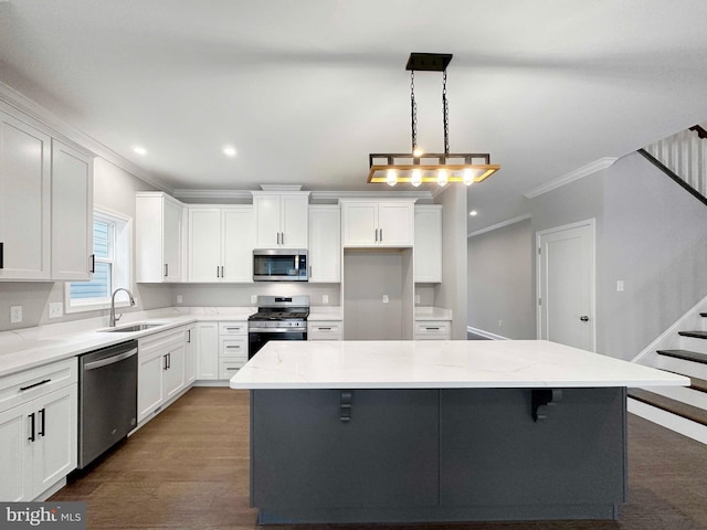 kitchen with pendant lighting, stainless steel appliances, a center island, ornamental molding, and dark hardwood / wood-style floors