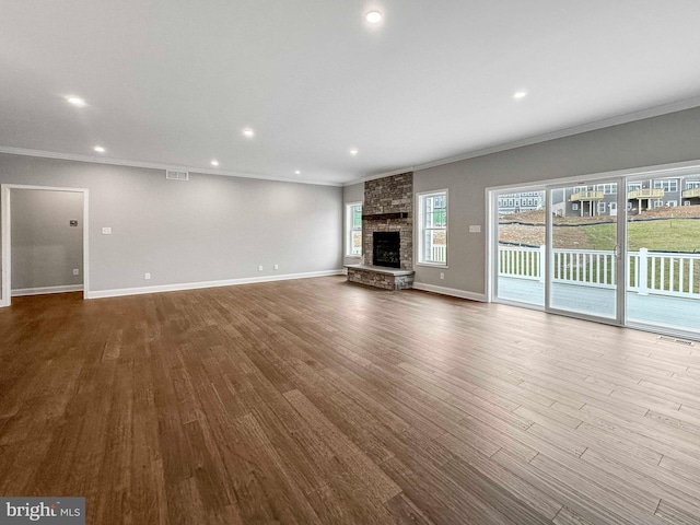 unfurnished living room with hardwood / wood-style floors, a stone fireplace, crown molding, and brick wall