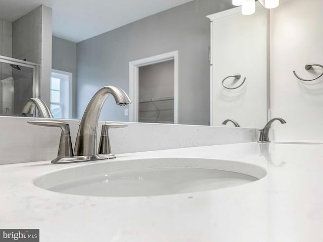 bathroom featuring a shower with shower door and sink