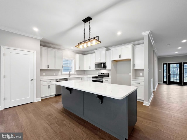 kitchen with white cabinetry, a center island, appliances with stainless steel finishes, and dark hardwood / wood-style flooring