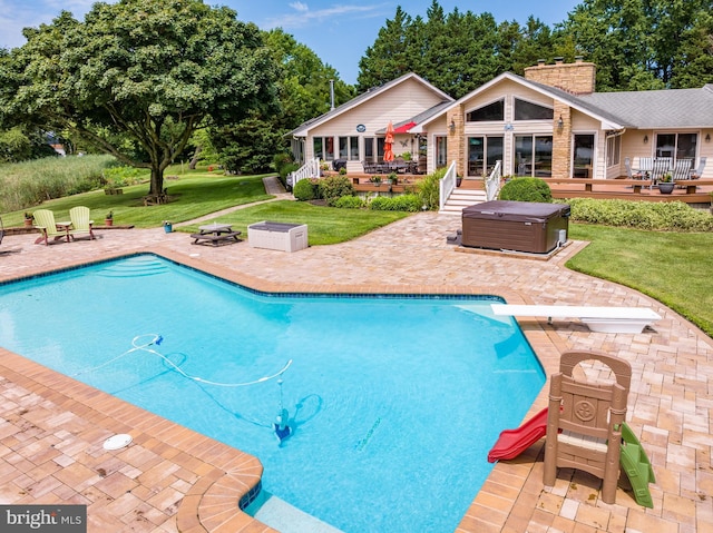 view of pool with an outdoor fire pit, a patio, a wooden deck, and a diving board