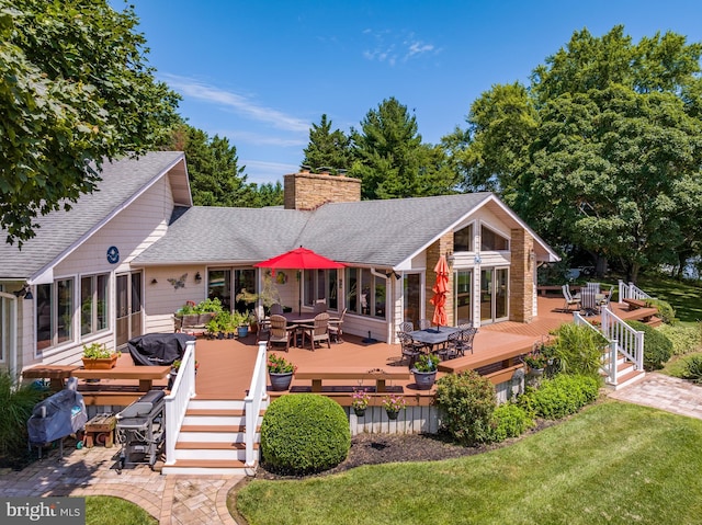 back of property featuring a deck and a lawn