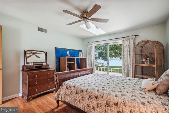 bedroom featuring access to exterior, ceiling fan, a skylight, and light hardwood / wood-style flooring