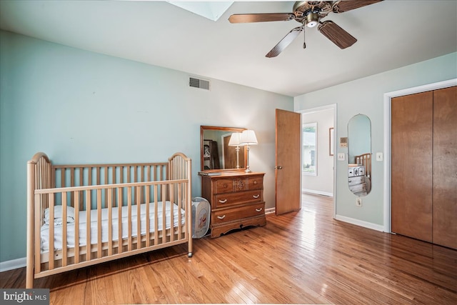 bedroom featuring ceiling fan, a crib, and light hardwood / wood-style floors