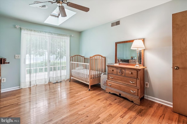 bedroom featuring a skylight, light hardwood / wood-style floors, and ceiling fan