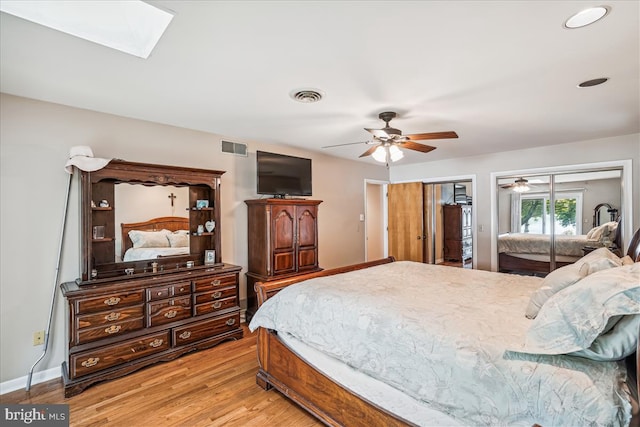 bedroom featuring access to exterior, ceiling fan, a skylight, and light hardwood / wood-style flooring