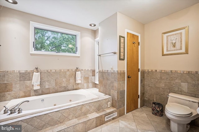 bathroom with tile floors, tile walls, toilet, and tiled bath