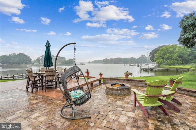 view of patio / terrace with an outdoor fire pit, a water view, and a dock