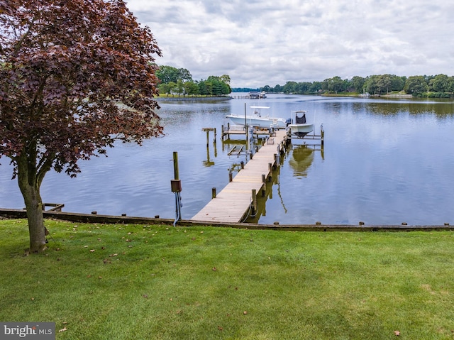 view of dock with a water view and a lawn