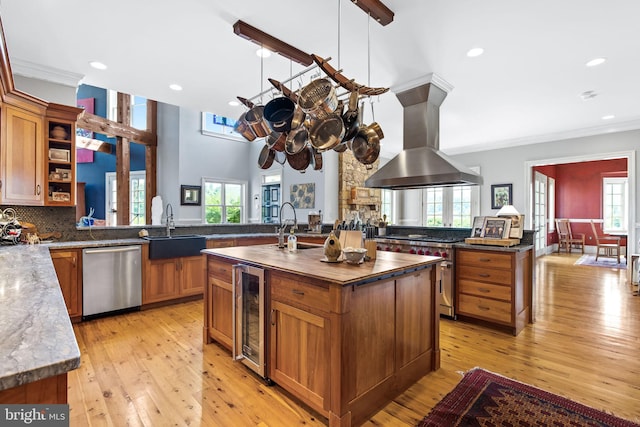 kitchen with a center island with sink, sink, wine cooler, island exhaust hood, and stainless steel appliances