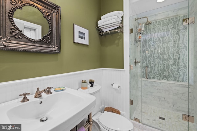 bathroom featuring toilet, a shower with door, and sink