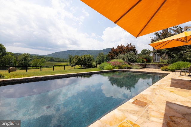 view of swimming pool with a mountain view, a yard, and a patio area