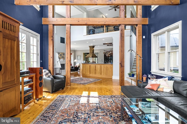 living room featuring high vaulted ceiling, french doors, light hardwood / wood-style flooring, ceiling fan, and beamed ceiling