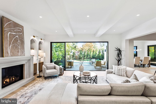 living room featuring beam ceiling, a healthy amount of sunlight, and light wood-type flooring