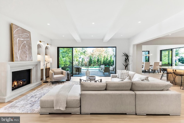 living room with light hardwood / wood-style floors, a healthy amount of sunlight, and beam ceiling