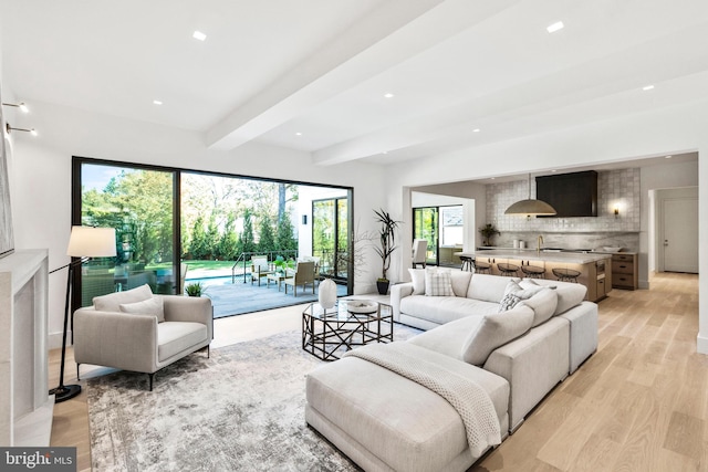 living room featuring light hardwood / wood-style flooring, beam ceiling, and a wealth of natural light