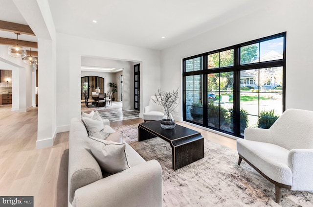 living room featuring beamed ceiling and light wood-type flooring