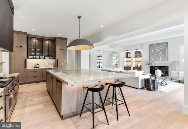 kitchen featuring light hardwood / wood-style floors, sink, a center island with sink, and double oven range