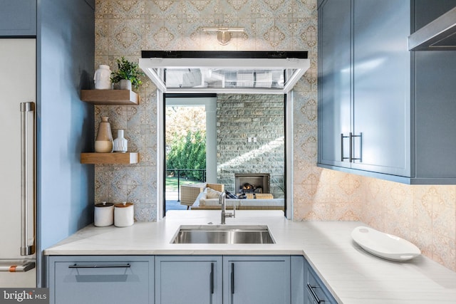 kitchen with blue cabinetry, sink, and tasteful backsplash