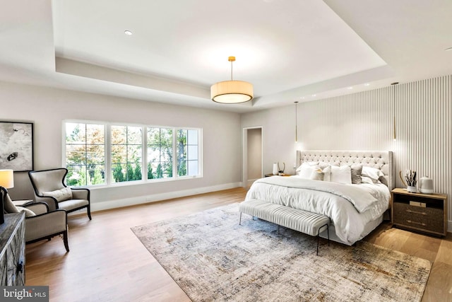 bedroom featuring a tray ceiling and light hardwood / wood-style floors