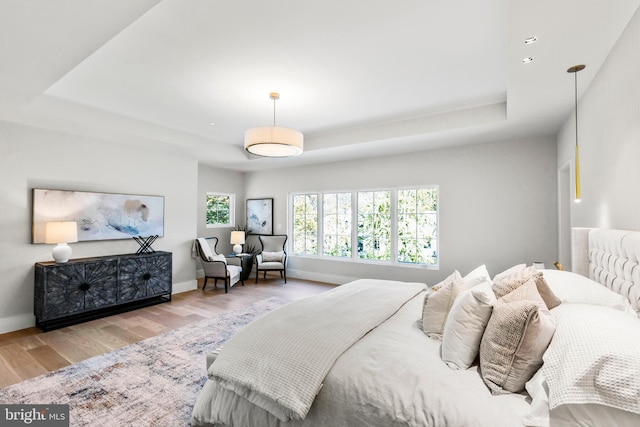 bedroom featuring a tray ceiling and light wood-type flooring