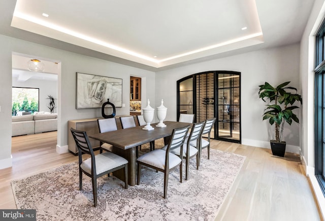 dining room with a tray ceiling and light wood-type flooring