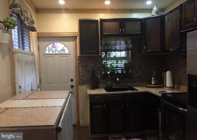 kitchen with backsplash, sink, range with electric cooktop, crown molding, and dark brown cabinetry