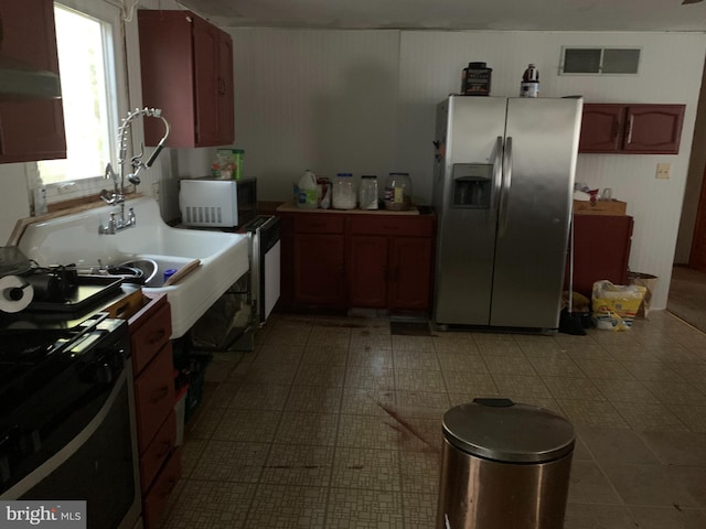 kitchen with stainless steel fridge, stove, sink, and light tile flooring