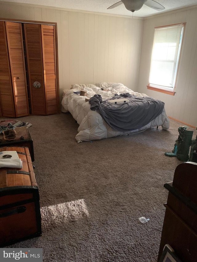 carpeted bedroom with a textured ceiling, a closet, and ceiling fan