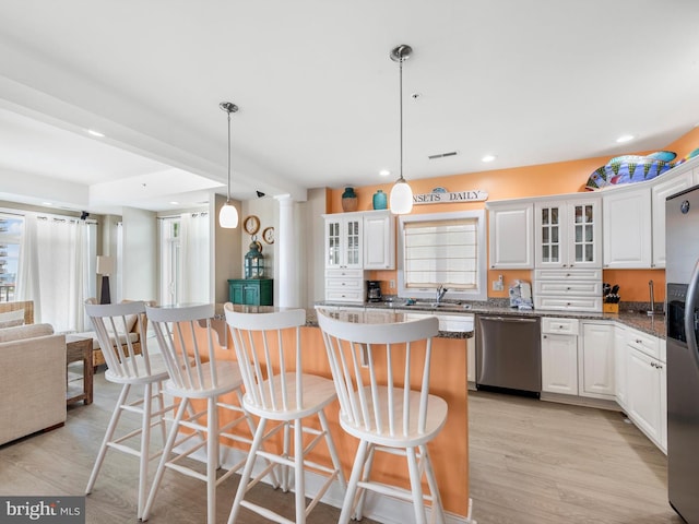 kitchen featuring hanging light fixtures, white cabinets, appliances with stainless steel finishes, and light wood-type flooring