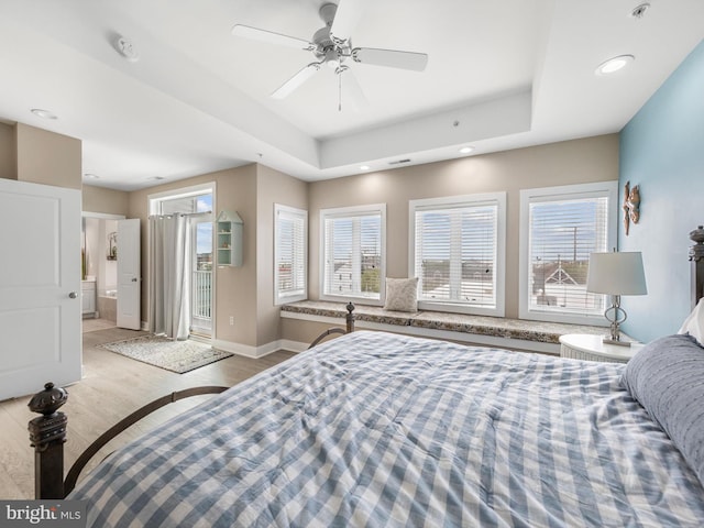 bedroom featuring a tray ceiling, ceiling fan, and light wood-type flooring