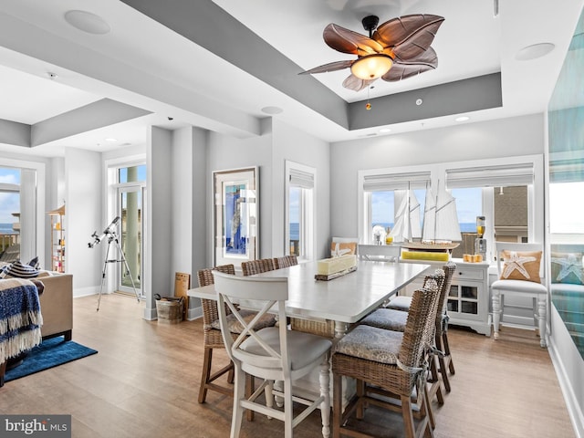 dining room featuring ceiling fan, a raised ceiling, and light hardwood / wood-style floors