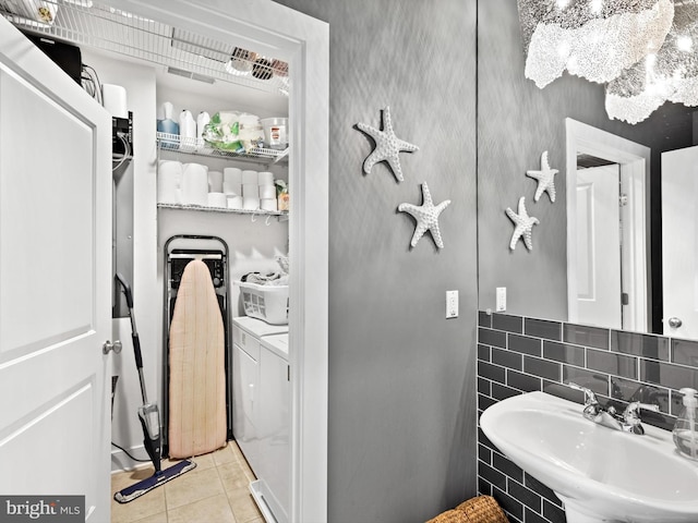 bathroom with washing machine and clothes dryer, sink, and tile floors