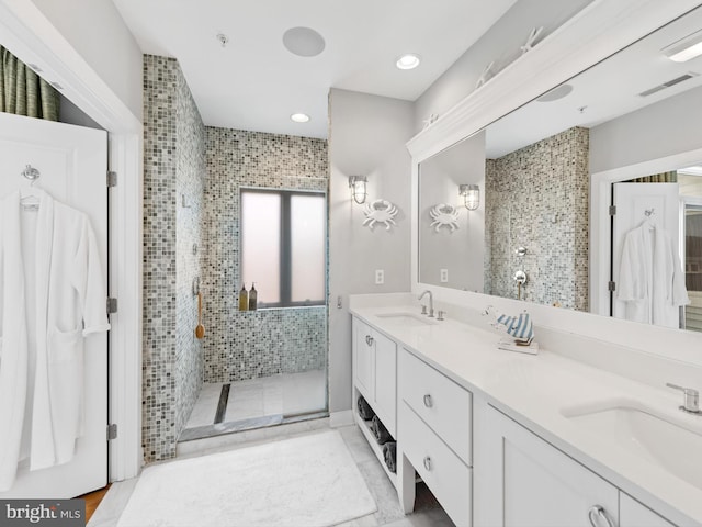 bathroom featuring a shower with door, dual sinks, and large vanity