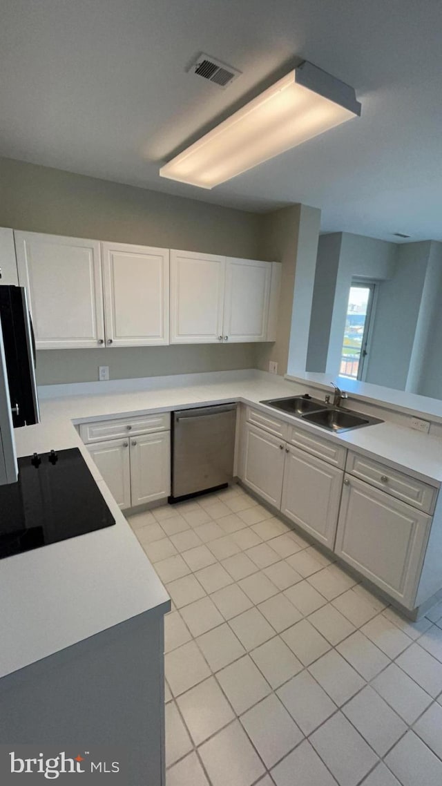 kitchen with kitchen peninsula, sink, light tile floors, stainless steel dishwasher, and white cabinetry