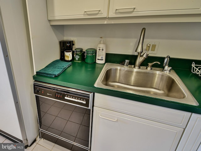 kitchen with black dishwasher, sink, white cabinetry, and light tile floors