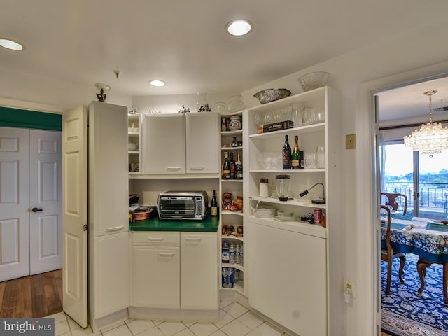 interior space featuring hanging light fixtures, a chandelier, light tile flooring, and white cabinetry