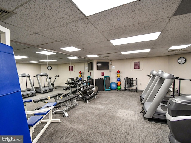 exercise room with dark colored carpet and a paneled ceiling