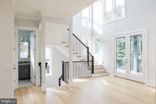 entryway featuring sink, a high ceiling, light hardwood / wood-style floors, and french doors