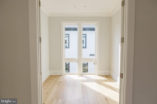 unfurnished room featuring plenty of natural light, ornamental molding, and light wood-type flooring