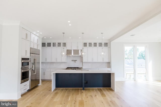 kitchen featuring white cabinetry, pendant lighting, stainless steel appliances, and a kitchen island with sink