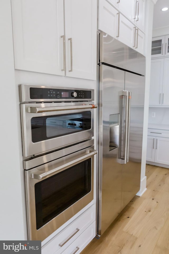 kitchen with white cabinets, appliances with stainless steel finishes, and light wood-type flooring