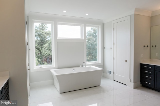 bathroom with tile floors, a bathing tub, and vanity