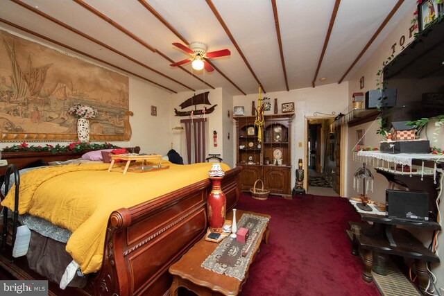 carpeted bedroom with ceiling fan and beamed ceiling