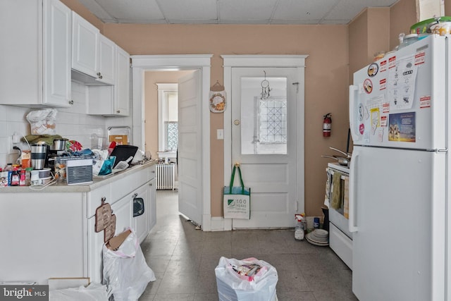 kitchen with white appliances, a paneled ceiling, light tile flooring, and white cabinetry